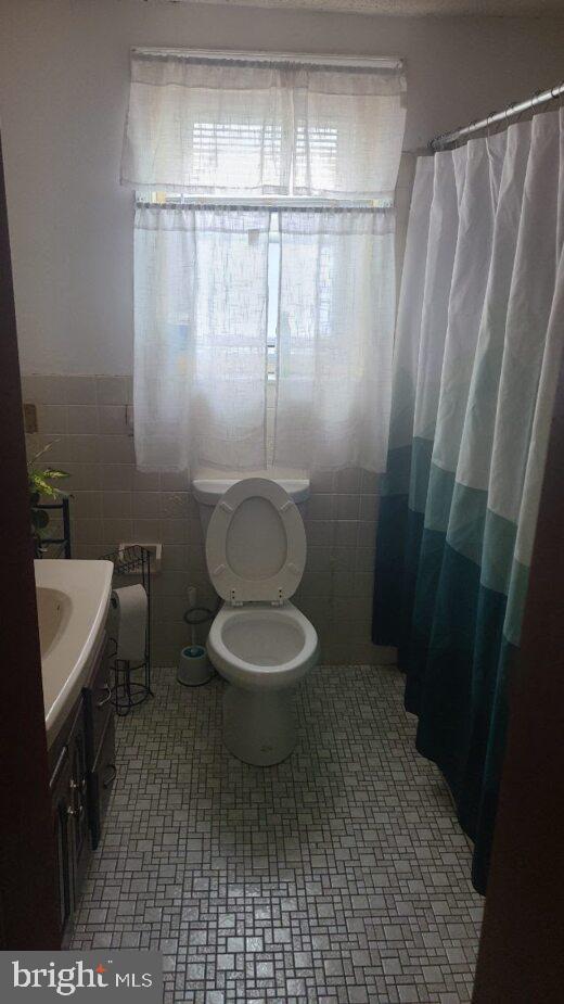 bathroom featuring tile walls, vanity, a shower with curtain, and toilet