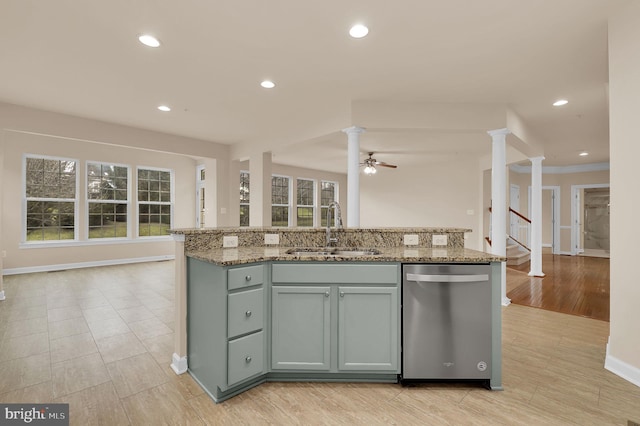 kitchen featuring sink, stainless steel dishwasher, an island with sink, stone counters, and decorative columns