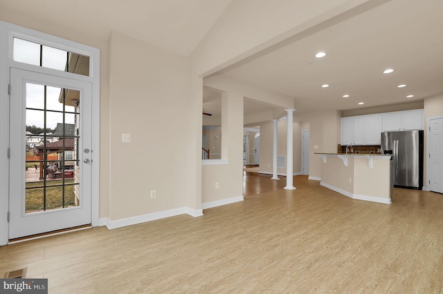 unfurnished living room with light hardwood / wood-style flooring and ornate columns