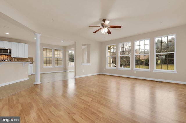 unfurnished living room with decorative columns, ceiling fan, and light wood-type flooring