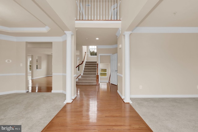 foyer entrance with crown molding, light hardwood / wood-style flooring, and ornate columns