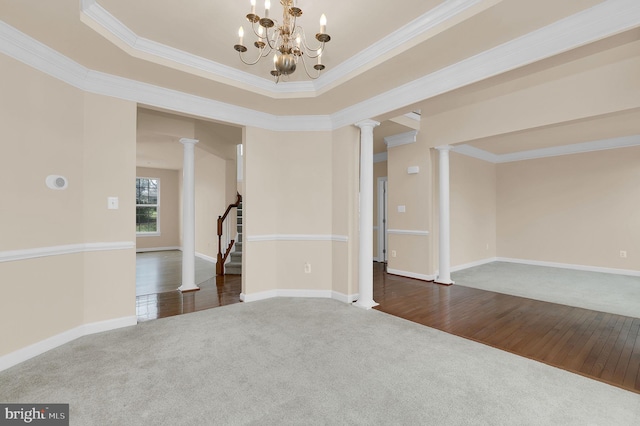 spare room featuring crown molding, a raised ceiling, decorative columns, and dark colored carpet