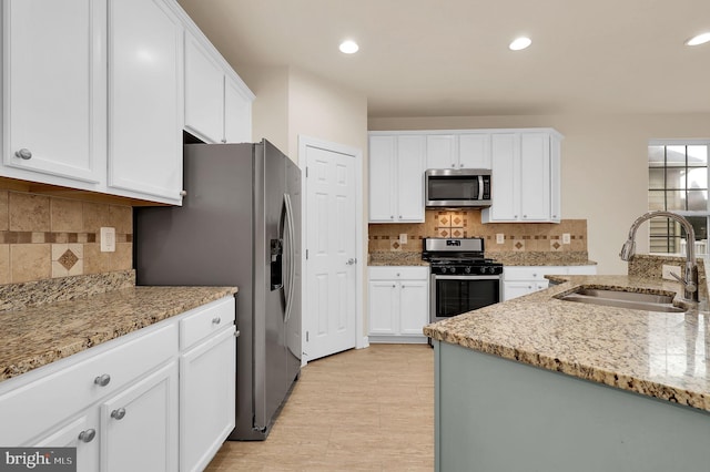 kitchen featuring white cabinetry, sink, backsplash, light stone counters, and stainless steel appliances