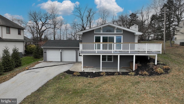 back of property featuring a garage, a yard, and a deck