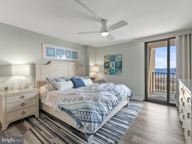 bedroom featuring hardwood / wood-style flooring, a water view, access to exterior, and ceiling fan