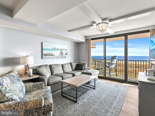 living room featuring beam ceiling, a water view, a notable chandelier, wood-type flooring, and expansive windows