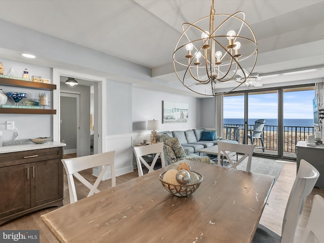 dining room featuring hardwood / wood-style floors, a chandelier, and a water view