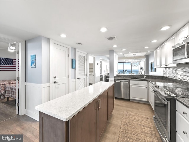 kitchen featuring dark hardwood / wood-style floors, a kitchen island, white cabinets, stainless steel appliances, and backsplash