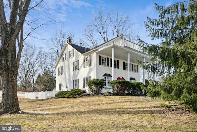 view of side of property with a yard, a chimney, and fence