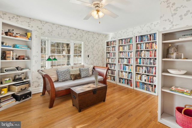 sitting room with wallpapered walls, a ceiling fan, and wood finished floors