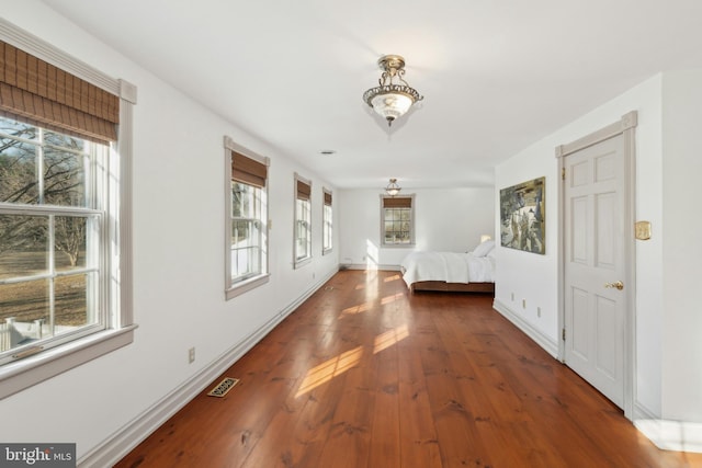 hall featuring wood-type flooring, visible vents, plenty of natural light, and baseboards