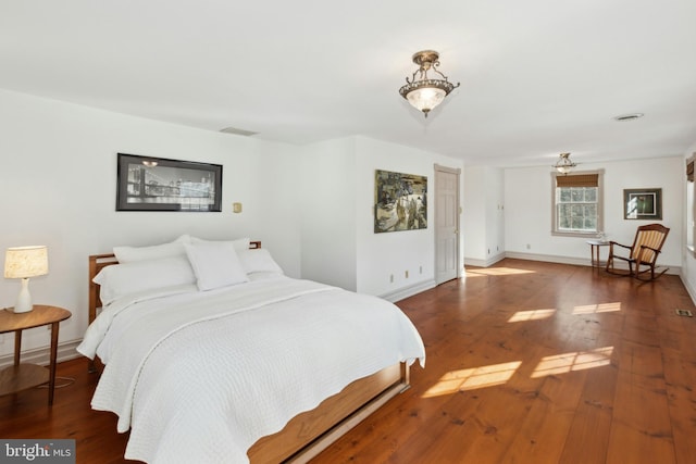 bedroom with wood-type flooring, visible vents, and baseboards