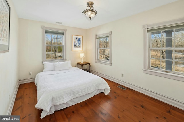 bedroom with wood-type flooring, visible vents, and baseboards