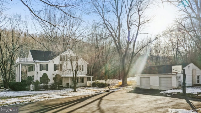 view of front facade with a detached garage, an outdoor structure, and a balcony