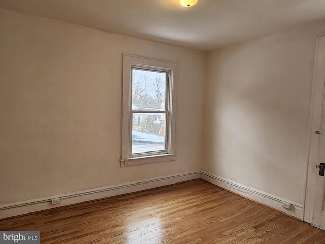 empty room with a baseboard heating unit and light hardwood / wood-style floors