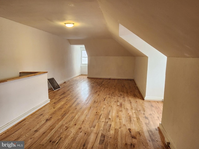 additional living space featuring lofted ceiling and light hardwood / wood-style floors