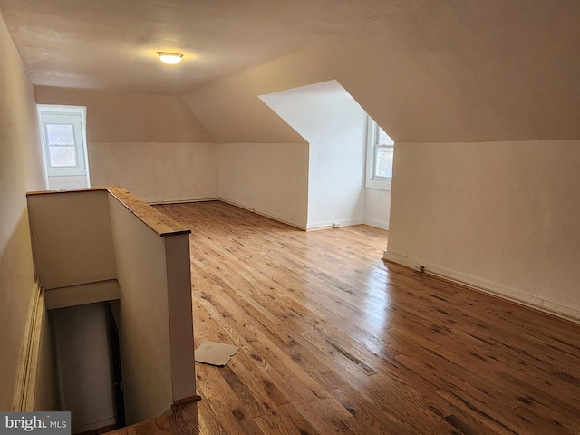 additional living space with hardwood / wood-style flooring and lofted ceiling