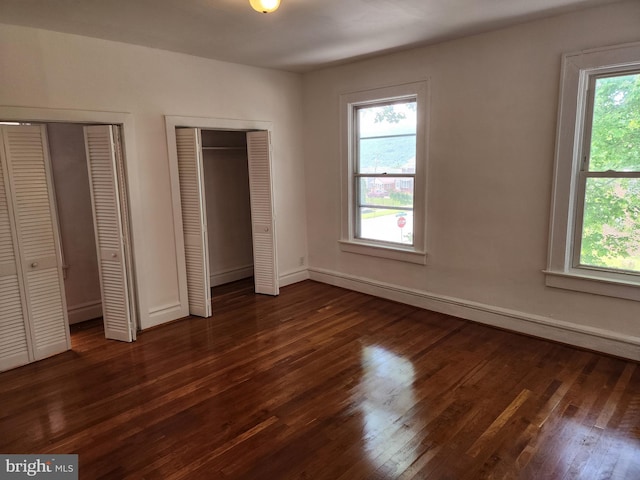 unfurnished bedroom featuring two closets and dark hardwood / wood-style flooring