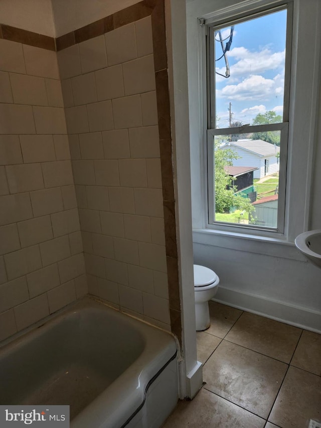 bathroom featuring a washtub, tile patterned flooring, and toilet