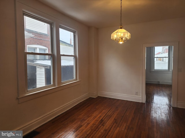 empty room featuring dark hardwood / wood-style floors and a notable chandelier