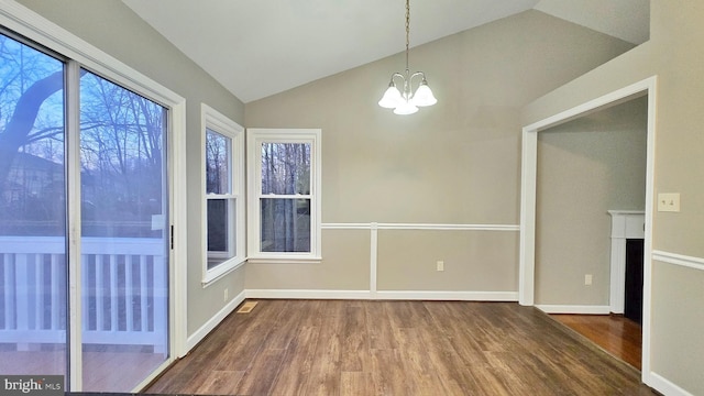 unfurnished room with hardwood / wood-style floors, lofted ceiling, and an inviting chandelier