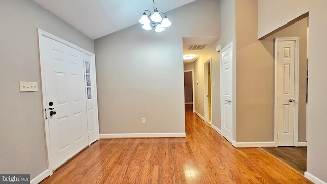 entryway with lofted ceiling, an inviting chandelier, and light hardwood / wood-style floors