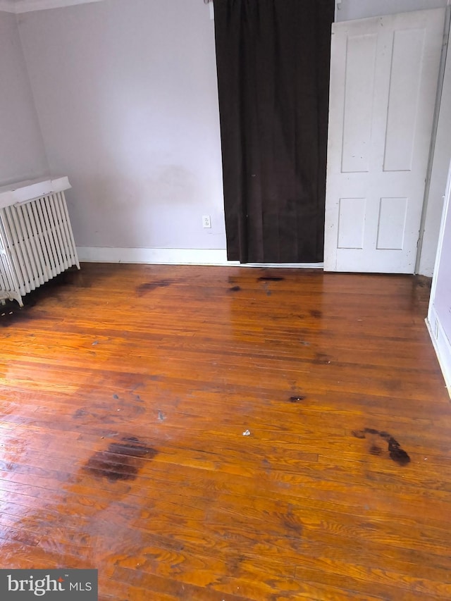 spare room with dark hardwood / wood-style flooring and radiator