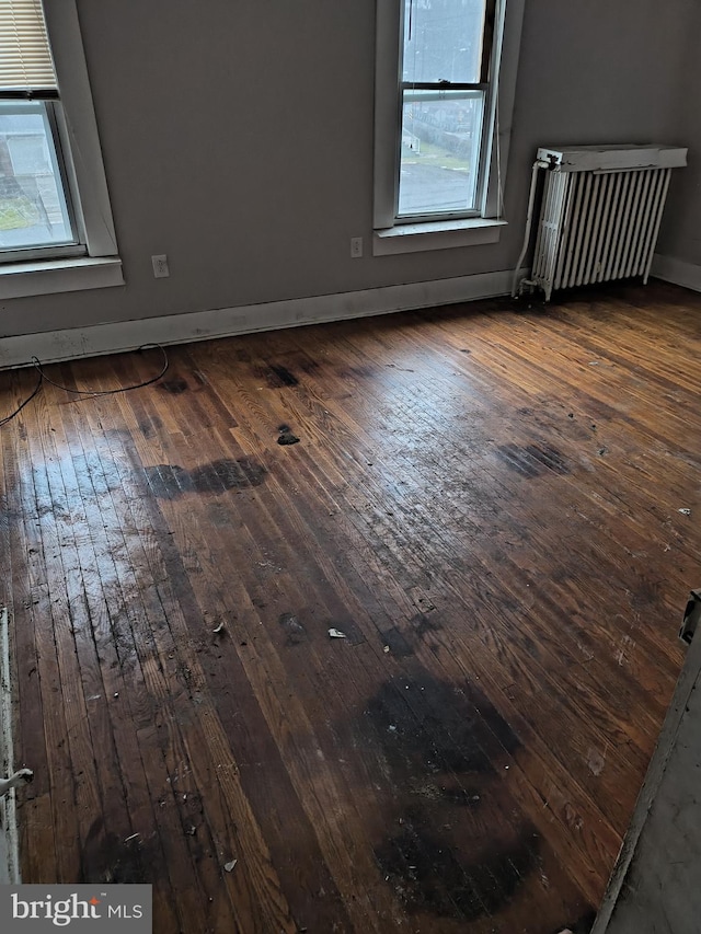 empty room with radiator and dark hardwood / wood-style flooring