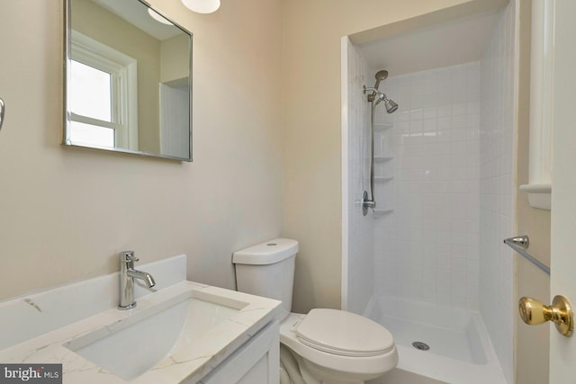 bathroom featuring vanity, toilet, and tiled shower