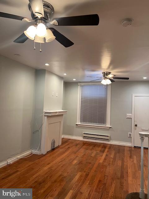 unfurnished living room featuring hardwood / wood-style floors, ceiling fan, and baseboard heating