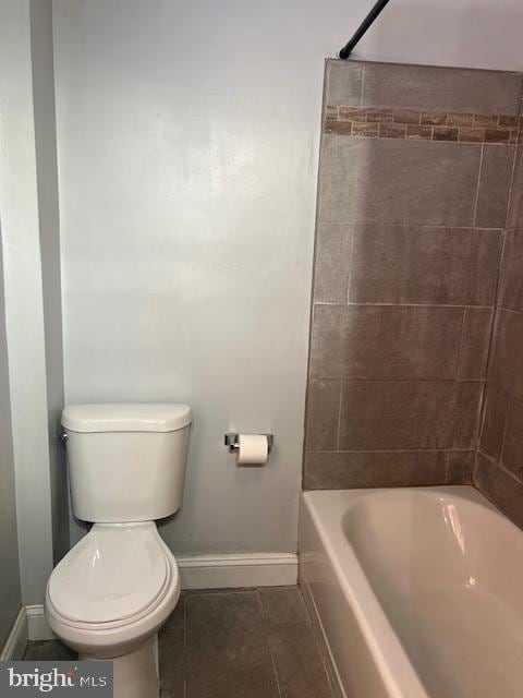 bathroom with toilet, tiled shower / bath combo, and tile patterned flooring