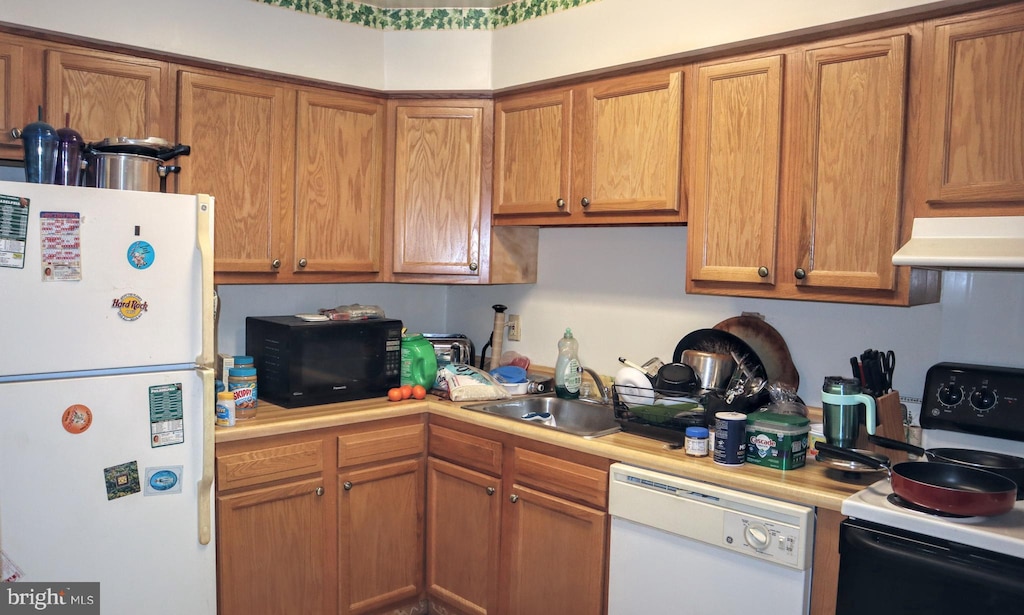 kitchen with white appliances, light countertops, a sink, and under cabinet range hood