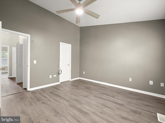 unfurnished bedroom with wood finished floors, baseboards, high vaulted ceiling, and ceiling fan