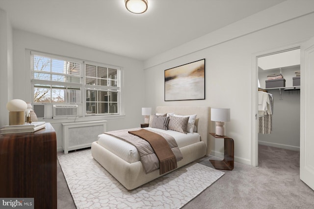 bedroom featuring radiator, cooling unit, a walk in closet, light carpet, and a closet