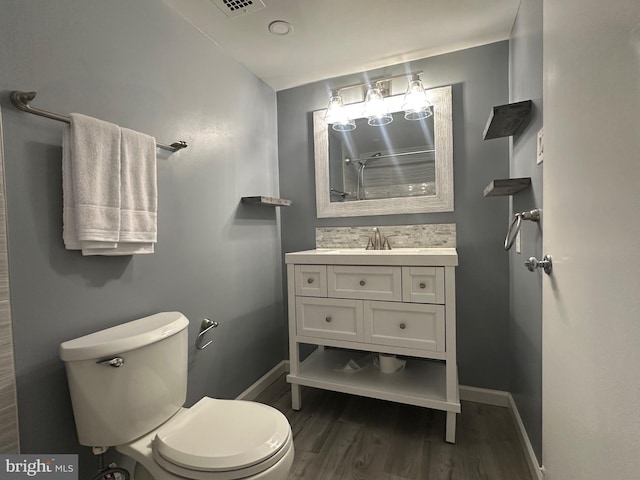 bathroom with vanity, wood finished floors, toilet, and baseboards