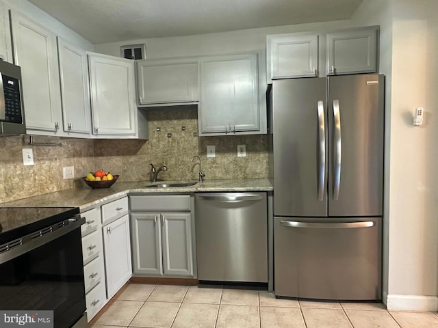 kitchen featuring tasteful backsplash, stainless steel appliances, a sink, and light tile patterned flooring