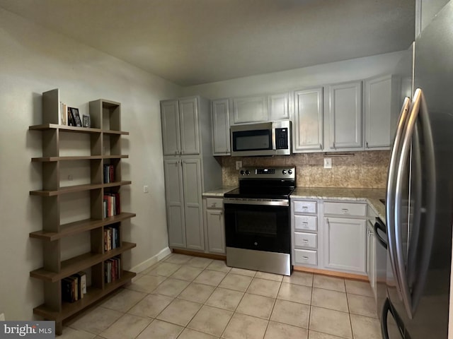 kitchen featuring light tile patterned floors, baseboards, decorative backsplash, appliances with stainless steel finishes, and white cabinetry