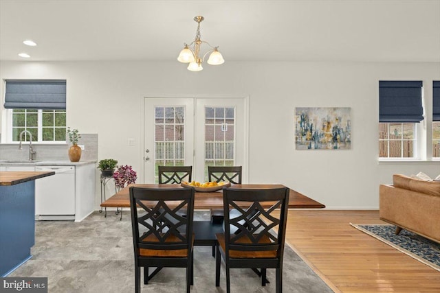 dining room with an inviting chandelier, sink, and light wood-type flooring