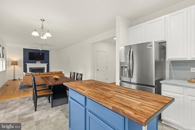 kitchen featuring hanging light fixtures, white cabinets, butcher block countertops, and stainless steel fridge with ice dispenser