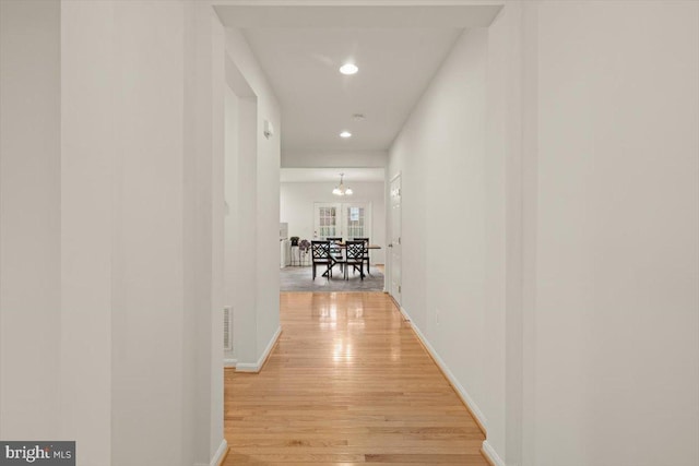 hall featuring light hardwood / wood-style floors and a chandelier