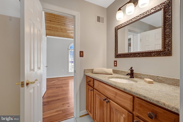 bathroom featuring visible vents, vanity, baseboards, and wood finished floors