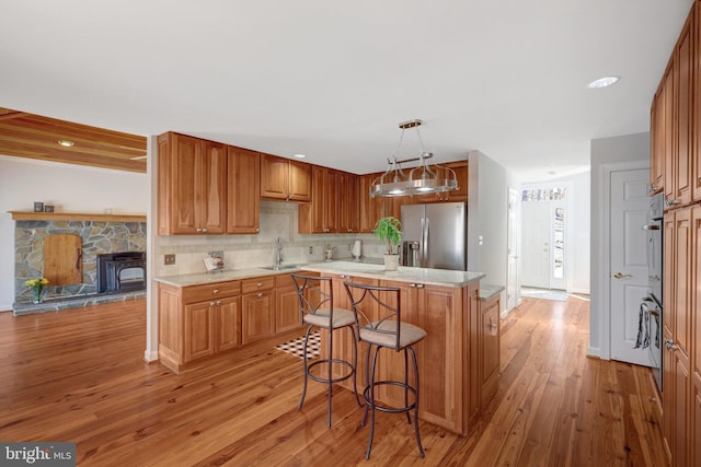 kitchen with light wood finished floors, decorative backsplash, a center island, stainless steel refrigerator with ice dispenser, and a sink