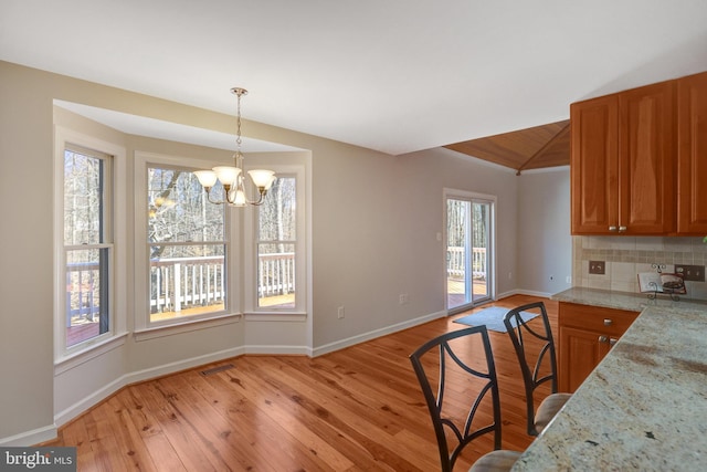 kitchen with light wood finished floors, visible vents, brown cabinetry, and backsplash