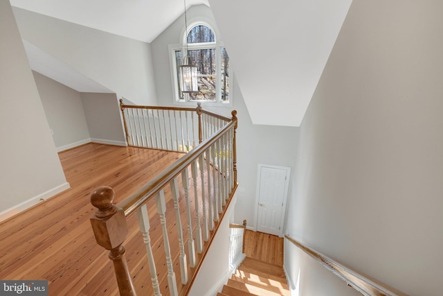 stairs featuring high vaulted ceiling, wood finished floors, and baseboards