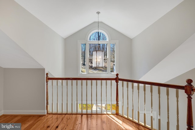 hall featuring lofted ceiling, baseboards, and wood finished floors