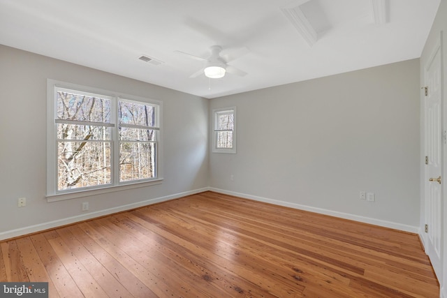 empty room with baseboards, visible vents, ceiling fan, and light wood finished floors