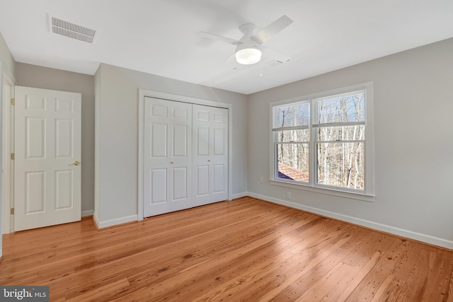 unfurnished bedroom featuring a ceiling fan, visible vents, baseboards, a closet, and light wood finished floors