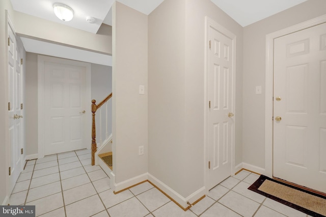 foyer entrance featuring light tile patterned floors, stairs, and baseboards