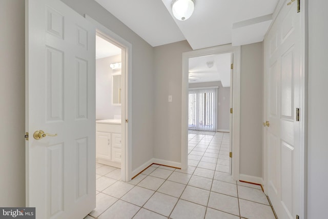 corridor featuring baseboards and light tile patterned flooring