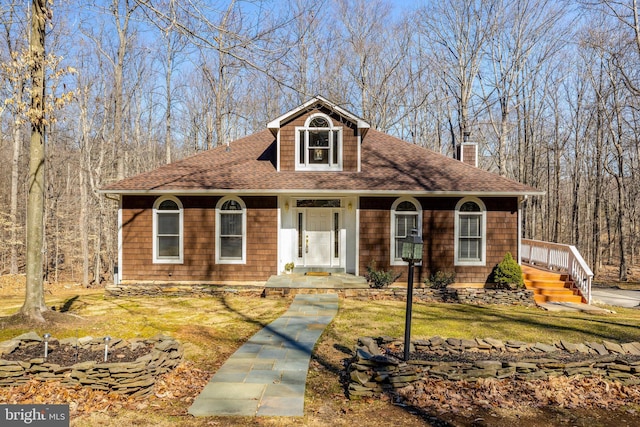 view of front facade featuring a chimney, a front lawn, and roof with shingles